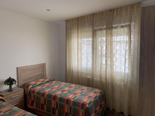 a bedroom with a bed and a window with curtains at Casa Conricado in O Grove