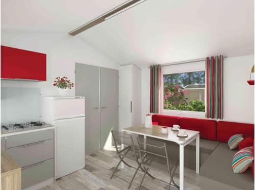 Il comprend une cuisine et un salon avec un canapé rouge et une table. dans l'établissement Domaine Résidentiel de Plein Air La Canadienne, à Arès