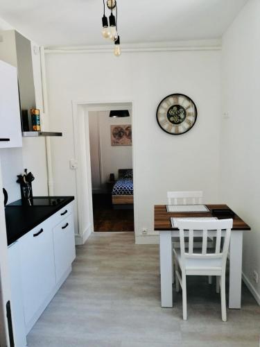 une cuisine avec une table et une horloge au mur dans l'établissement Uluru - Centre Ville - Poitiers, à Poitiers