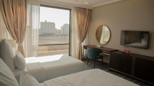 a hotel room with two beds and a desk and a window at فندق سدو بوتيك Hotel SDU BOUTIQUE in Jazan
