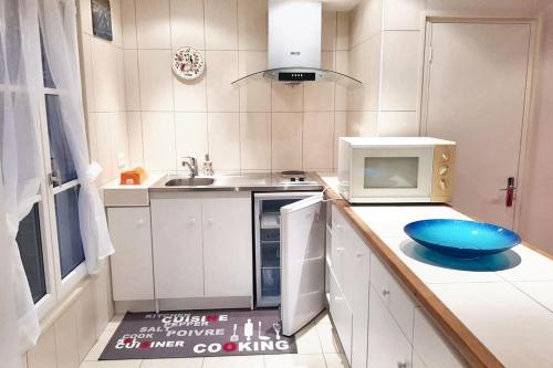 - une cuisine équipée d'un four micro-ondes et d'un bol bleu sur le comptoir dans l'établissement Maison de charme à Gacé avec barbecue et parking, à Gacé