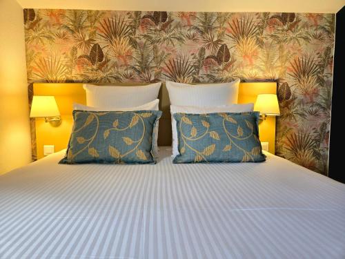 a bedroom with a bed with two pillows and a wallpaper at Hôtel Le SAINT-GENIÈS in Uzès