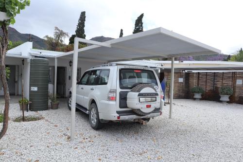 a white car parked under a canopy in front of a house at River Bend Guesthouses in Graaff-Reinet