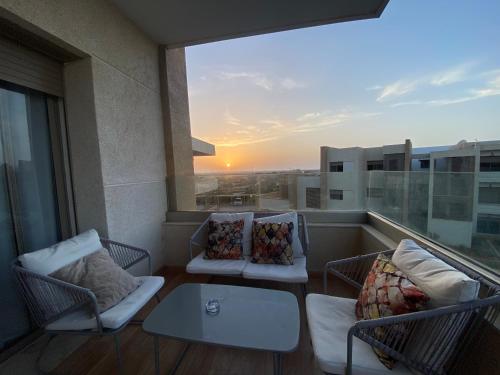 a balcony with two chairs and a table and a sunset at Appartement Tamaris in Saidia 