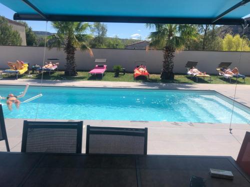 - une piscine entourée de chaises dans l'établissement Villa des mazes, à Vallon-Pont-dʼArc