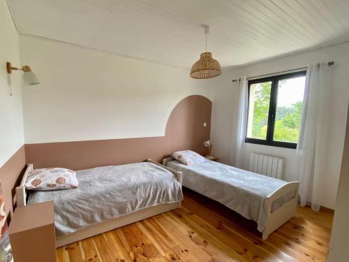 une chambre avec deux lits et une fenêtre dans l'établissement Gîte Le chant du grillon, à Saint-Étienne-de-Lugdarès