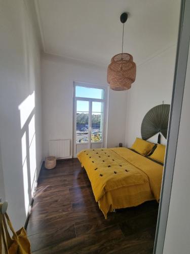 une chambre avec un lit jaune et une fenêtre dans l'établissement Cozy apartment, à LʼIsle-sur-la-Sorgue