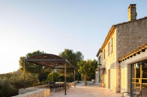 een patio met tafels en een paviljoen naast een gebouw bij Le Mas des Baux in Les Baux-de-Provence