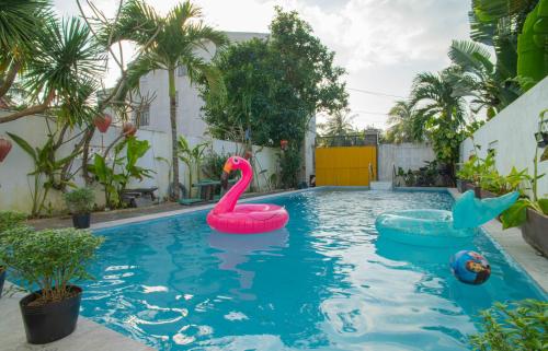 a pool with two inflatable flamingos in the water at ROMITTO RIVERSIDE in HOI AN POOL VILLA in Cam Thanh