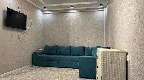a living room with a blue couch and a tv at Апартамент Азия in Bishkek