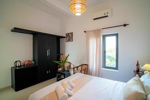 a bedroom with a white bed and a window at ROMITTO RIVERSIDE in HOI AN POOL VILLA in Cam Thanh