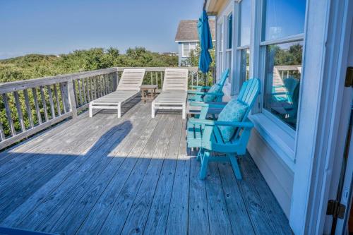 a porch with blue chairs and a table and chairs at Waterfront luxury w-beach resort-pool-golf-tennis-fishing & views! in Nags Head