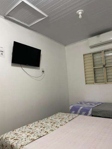 Un dormitorio con dos camas y un televisor de pantalla plana en la pared. en Casa da Mariângela, en São Gabriel