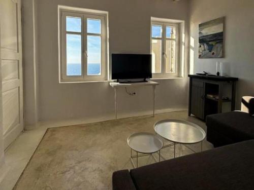 a living room with a couch and a tv at White Rock Suites & Villas in Houlakia
