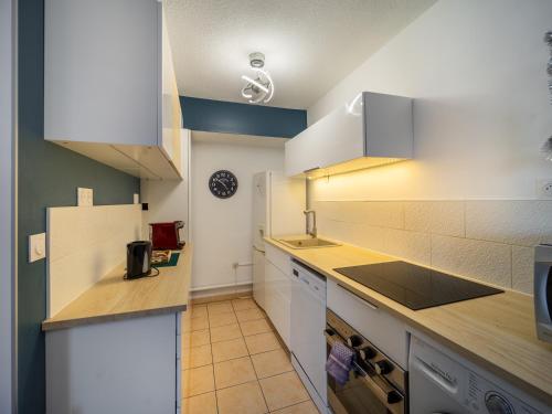 une cuisine avec des armoires blanches et un comptoir dans l'établissement Le Dory - Spacieux, Climatisation, Terrasse & Parking, à Montpellier