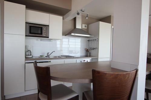 une cuisine avec une table et des chaises en bois dans l'établissement Bord de plage, appartement pour 12, vue mer, à La Tranche-sur-Mer