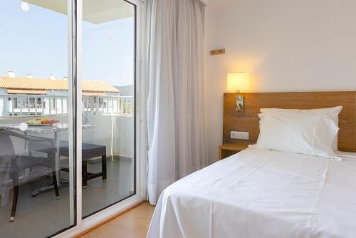 Un dormitorio con una cama y un balcón con una mesa. en Hipotels Apartamentos Cala Bona, en Cala Bona