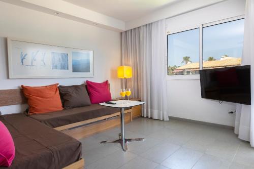 Una sala de estar con un sofá y un televisor. en Hipotels Apartamentos Cala Bona, en Cala Bona