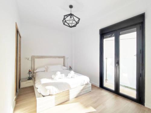 a white bedroom with a bed and a large window at Ohana home 2 in Málaga