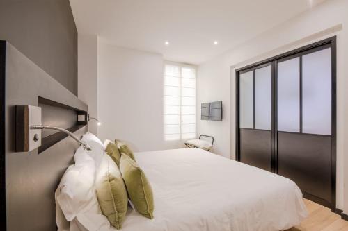 une chambre avec un lit avec des draps blancs et des oreillers dans l'établissement Scandinavian Urban 1 - 2BR apartment in center close to Palais des Festivals and the beach, à Cannes