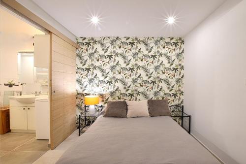- une chambre avec un lit et un mur recouvert de papier peint dans l'établissement Appartement au coeur de Vendémian, à Vendémian