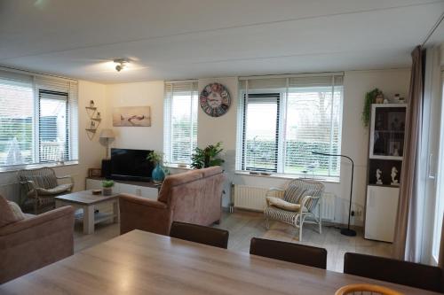 a living room with a table and chairs and a couch at Kustverhuur, Park Schoneveld, Stern 234 met eigen elektrische laadpaal in Breskens