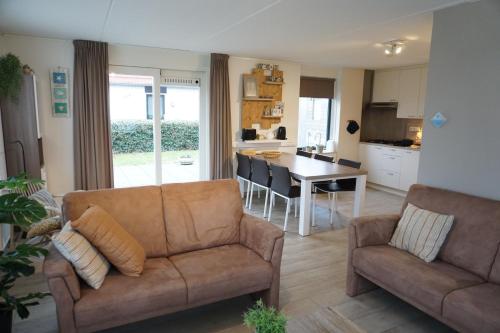 a living room with a couch and a table and a kitchen at Kustverhuur, Park Schoneveld, Stern 234 met eigen elektrische laadpaal in Breskens