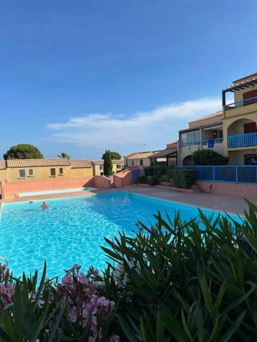 une grande piscine bleue à côté de certains bâtiments dans l'établissement VILLA DU PIN, à Gruissan