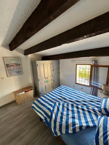 een slaapkamer met een bed met een blauw en wit dekbed bij VILLA DU PIN in Gruissan