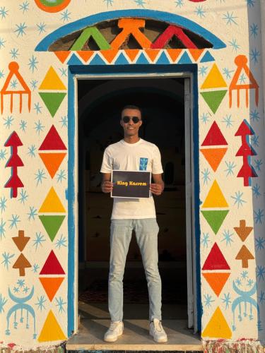 a man is holding a sign in a doorway at king kassem nubian guest house in Aswan