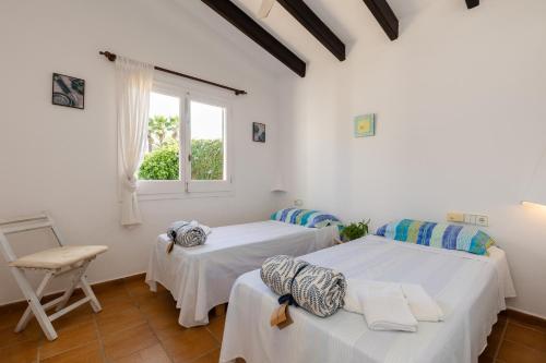 two beds in a white room with a window at Villa Esther vistas al mar Menorca in Cap d'en Font