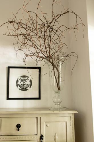 a vase with branches in it on top of a cabinet at River Bend Guesthouses in Graaff-Reinet