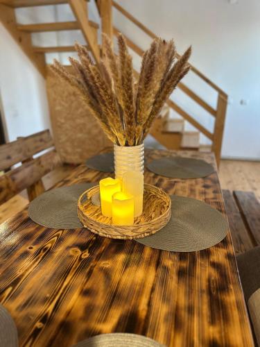a table with yellow candles and a vase with grass at Cabana dintre brazi in Muntele Băişorii
