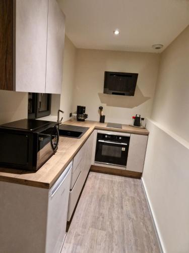 une cuisine avec des armoires blanches et un appareil noir dans l'établissement La Combe, à Aigueblanche