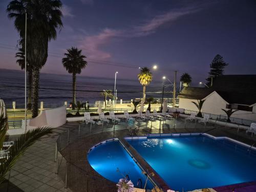a swimming pool with a view of the ocean at night at Departamento playa amarilla concón in Concón