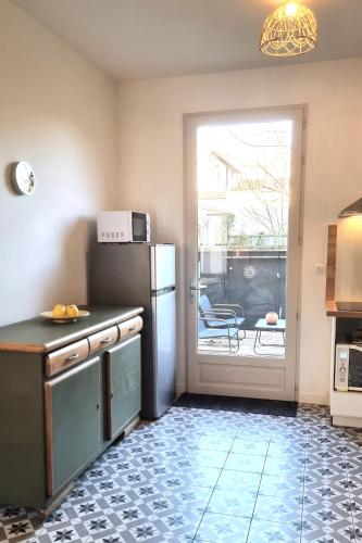 a kitchen with a refrigerator and a door to a patio at Maison de Charme en centre-ville in Libourne
