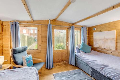 a bedroom with a bed and a chair and a window at Bay Tree Cottage - Cozy Norfolk Retreat in Heacham in Heacham
