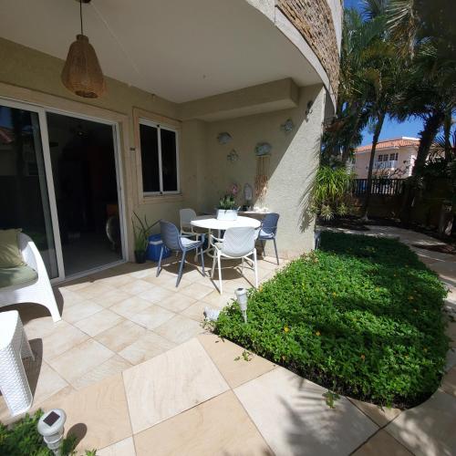 a patio with a table and chairs in a yard at Bohemian Townhouse Palm Beach Aruba in Palm-Eagle Beach