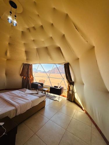 a bedroom with a bed and a large window at Rum Goldeneye luxury camp in Wadi Rum