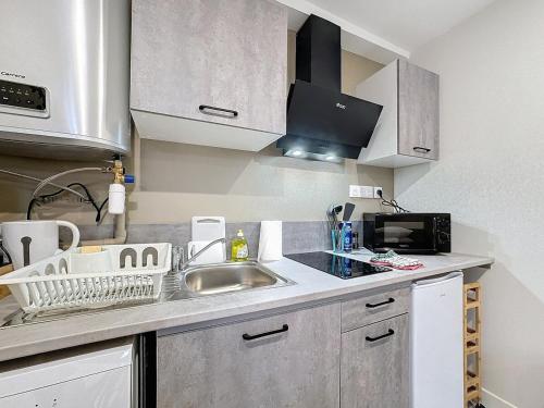 une cuisine avec un évier et un micro-ondes dans l'établissement Appartement tout neuf 4 pers N1, à Riom