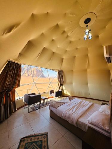 a bedroom with a bed and a large window at Rum Goldeneye luxury camp in Wadi Rum