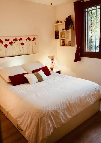 une chambre avec un grand lit blanc avec des oreillers rouges dans l'établissement Villamiclau2, à Fos-sur-Mer