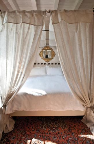 a white bed with curtains and a mirror at La Barchessa di Villa Pisani in Lonigo