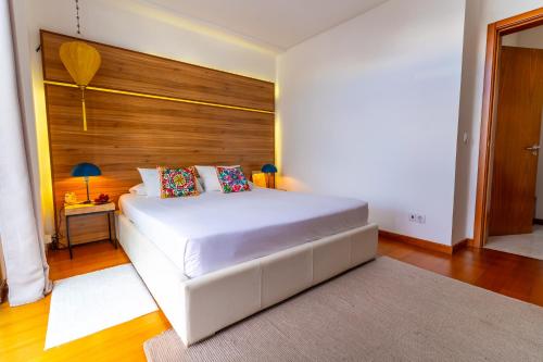 a bedroom with a white bed and a wooden wall at epicenter CITY in Ponta Delgada