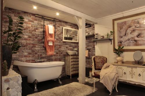 a bathroom with a brick wall and a bath tub at B&B De Zwerver in Oldehove