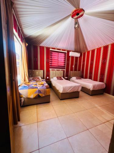 a room with three beds in a tent at Rum Goldeneye luxury camp in Wadi Rum
