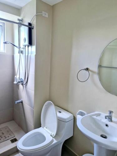 a white bathroom with a toilet and a sink at Avida Towers 2 Bedroom by PHI Rentals in Iloilo City