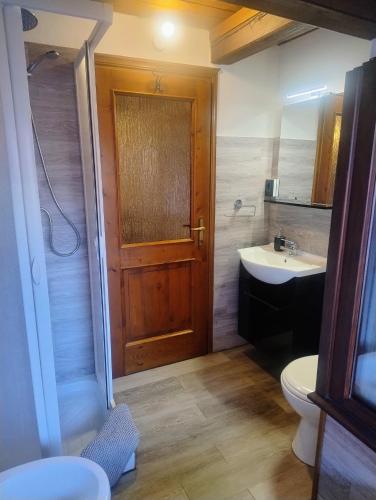 a bathroom with a wooden door and a sink at Cà d'Elsa in Pieve Vergonte