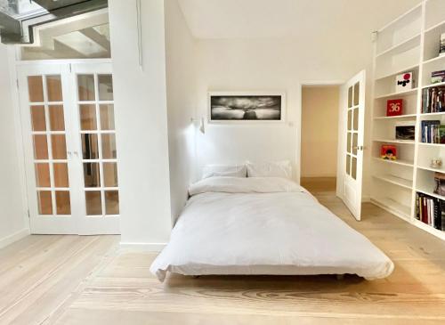 a white bedroom with a bed and bookshelves at Stunning 4 bed flat near Notting Hill and Hyde park in London