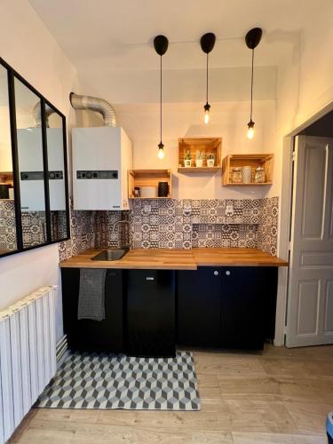 une cuisine avec des armoires noires et un comptoir dans l'établissement Suite en ville, à Aurillac